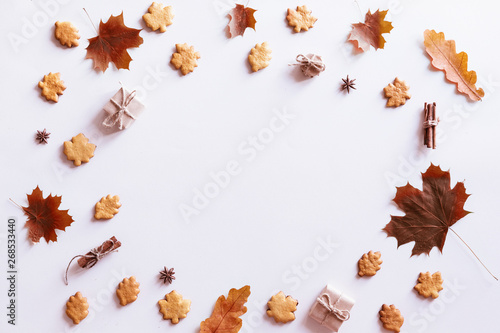 Hello Autumn flat lay background. Top view of wreath with maple leaves and yellow flowers, honey biscuits and cookies.