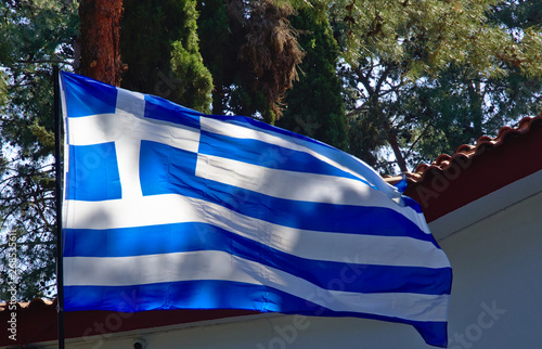 Wallpaper Mural Large Greek flag flapping in a park in front of church roof with tiles. Torontodigital.ca