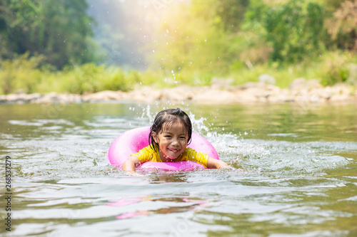 Little Asian girl in pool ring swimming in  river © AlivePhoto
