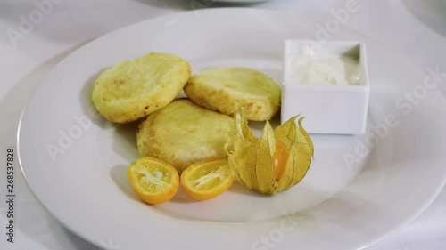 Close-up shot of three cheesecakes, orange, cape gooseberry and sour cream on a white plate. 4K photo