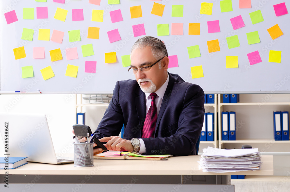 Aged man employee in conflicting priorities concept Aged man employee in conflicting priorities concept