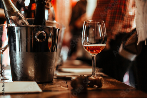 wine Tasting: a glass of rose wine stands on the tasting table next to brochures, champagne corks and silver buckets in which the wines are cooled.