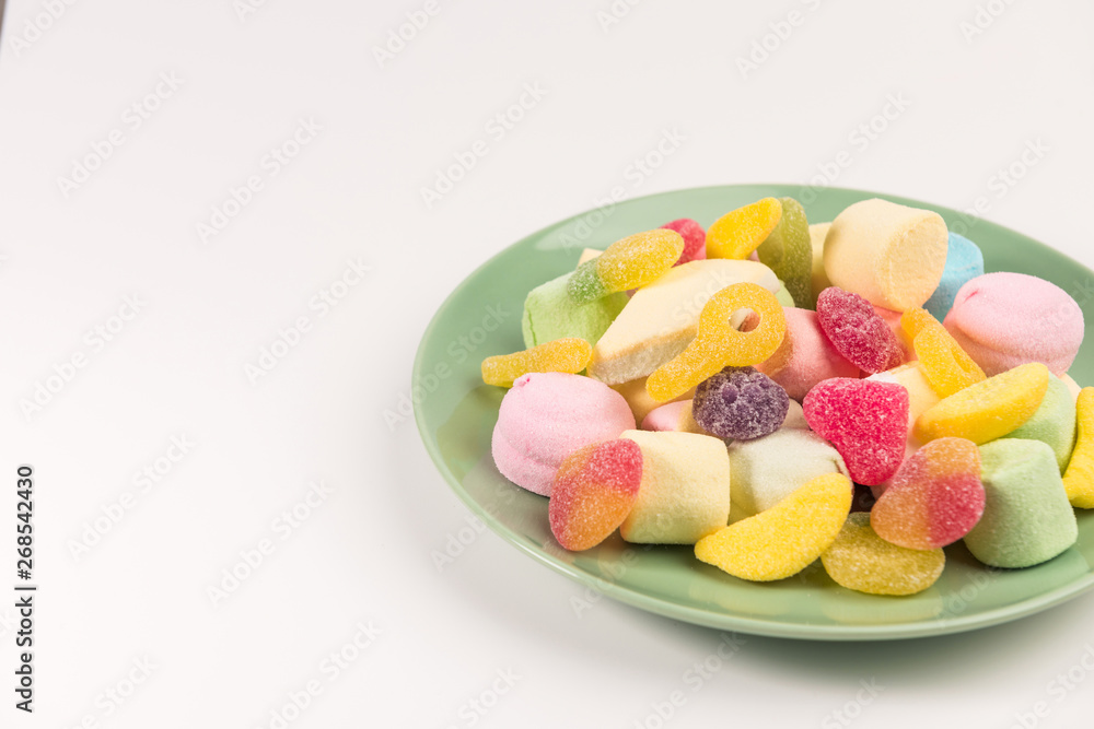 Plate with sweets isolated on a white background. Gummy candies and marshmallow. Plate with sweets isolated on a white background. Gummy candies and marshmallow.