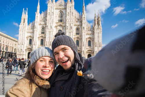 Travel, Italy and funny couple concept - Happy tourists taking a self portrait with pigeons in front of Duomo cathedral, Milan © satura_