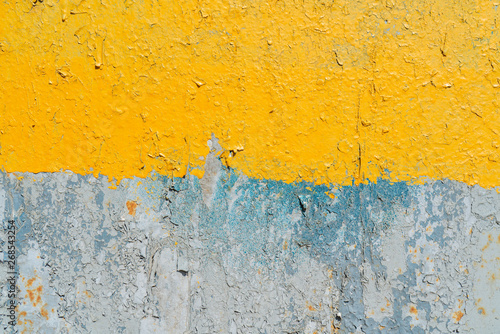 Yellow and gray cracked paint on a metal surface.