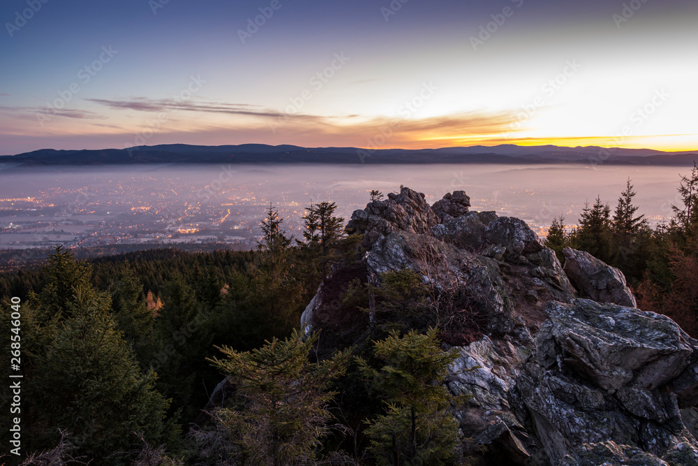 Sunrise above the town, which is covered by fog. The rock in foreground.