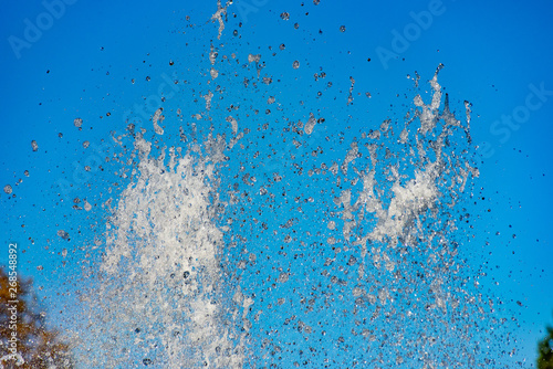 Splash of water against a blue sky and trees