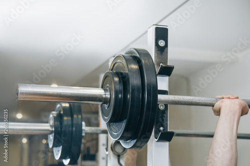 athlete with big hands holding a barbell bar in the training center. training tools in the gym close-up