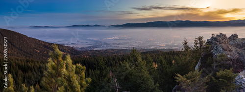 Sunrise above the town  which is covered by fog. The rock in foreground.