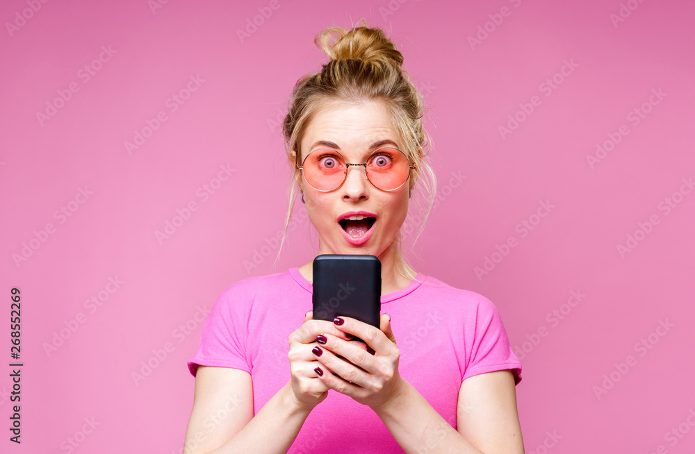 Photo of blonde woman in pink T-shirt with phone in her hands Photo of blonde woman in pink T-shirt with phone in her hands