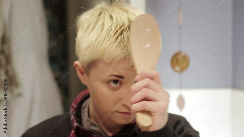 A short haired person struggling with brushing their hair just right. A short haired person struggling with brushing their hair just right.