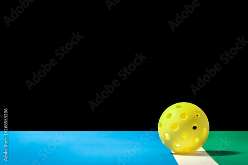 Small Yellow Pickleball with large background Yellow Pickleball on the boundry line of pickleball court and large background that can easily be remove and replaced.  Blue court area and green out of p