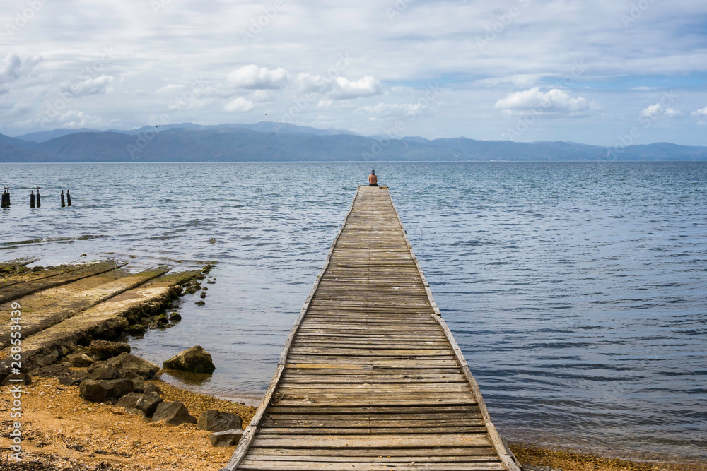 Fototapeta premium Woman resting on a old dock at the gulf of Cariaco in Venezuela