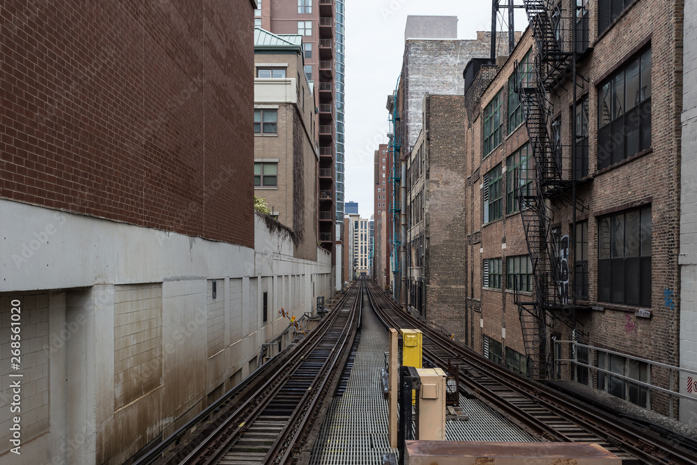 Looking down an train track alleyway between buildings in an urban setting