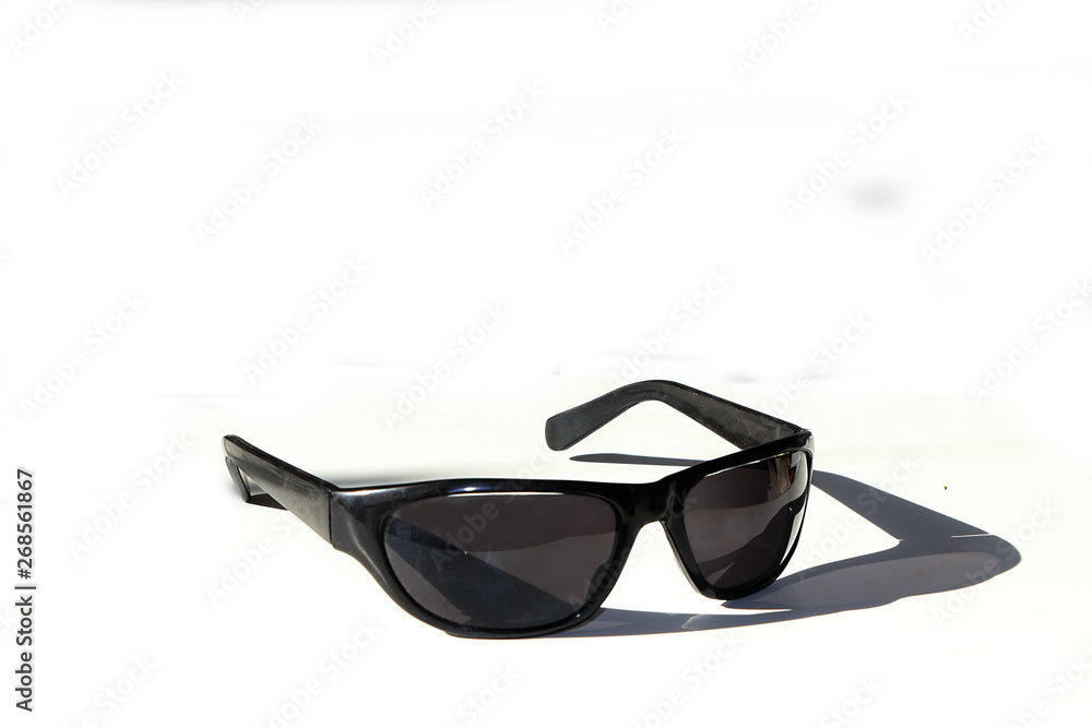 Black sunglasses on a white background with a shadow. Preparation for a sunny summer holiday Black sunglasses on a white background with a shadow. Preparation for a sunny summer holiday