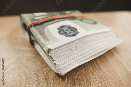 Wallpaper Mural bundle of money folded in half lying on a wooden table Torontodigital.ca