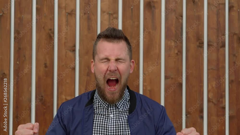 Angry young man is shouting and screaming, waving hands outdoor, medium shot Angry young man is shouting and screaming, waving hands outdoor, medium shot