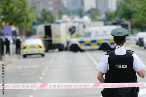 Police officer stands guard at a Police cordon point while army ATOs deal with a suspect bomb. photo