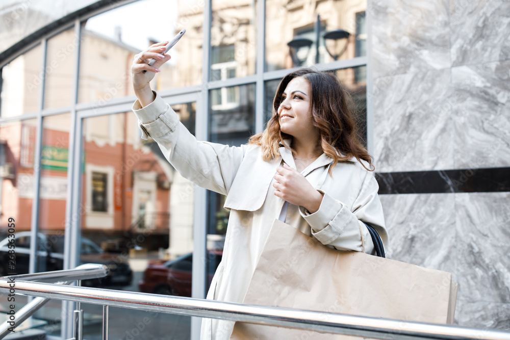 A young, sympathetic woman, not a thin-headed body building, walks around the city with a shopping bag, picks up herself on the phone, and has fun. Shopping and Leisure A young, sympathetic woman, not a thin-headed body building, walks around the city with a shopping bag, picks up herself on the phone, and has fun. Shopping and Leisure