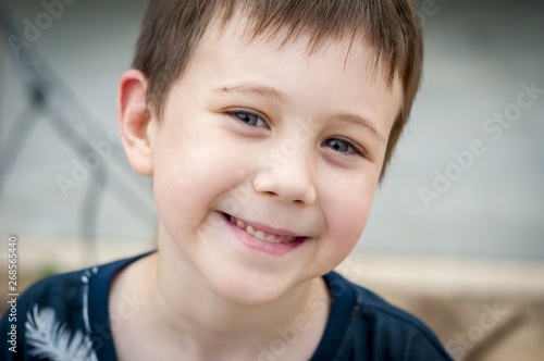 Elementary school age blue eyed Caucasian child boy looking at the camera closeup image. Smiling boy closeup portrait  positive attitude  happy childhood concept  chewing gum.