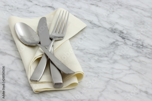 silverware and hemstitch napkin on antique carrara marble photo