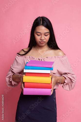 Unhappy young Asian woman studying with may books.