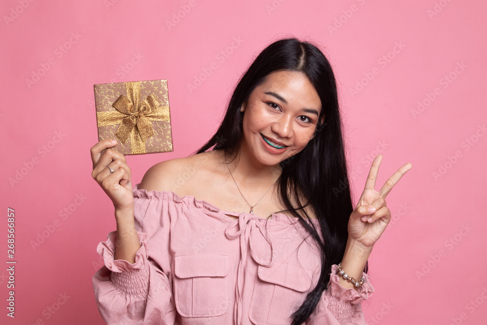 Asian woman show victory sign with a gift box. Asian woman show victory sign with a gift box.