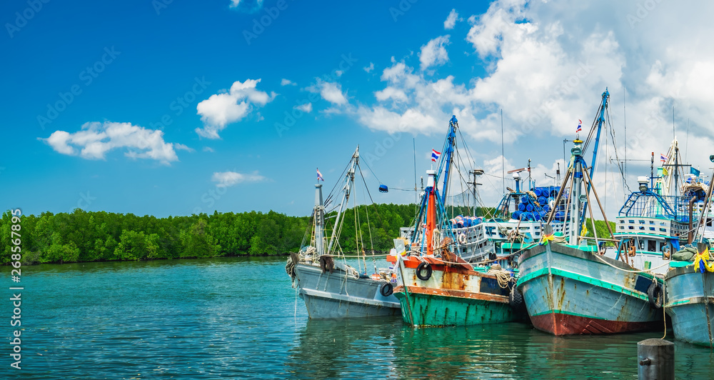 Small fishing boats docked to Khura Buri Pier, islands in the background, Khura Buri District, Phang-nga, Thailand