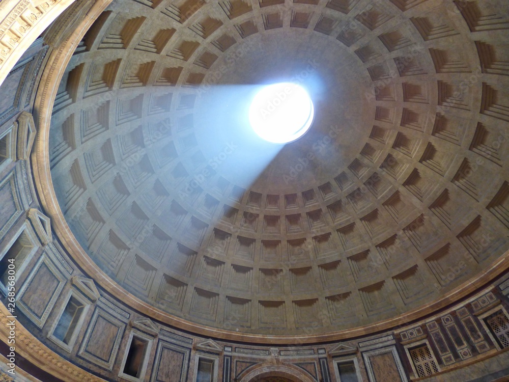 A view looking up at sunlight streaming through the dome of the Panteon in Rome Italy