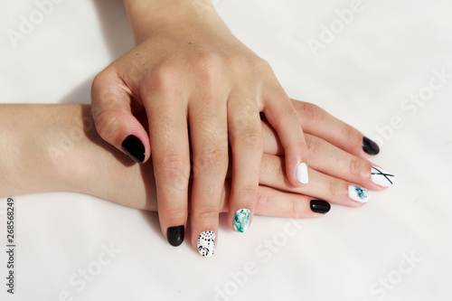 hands of a young girl with green, black and white manicure, with stickers.