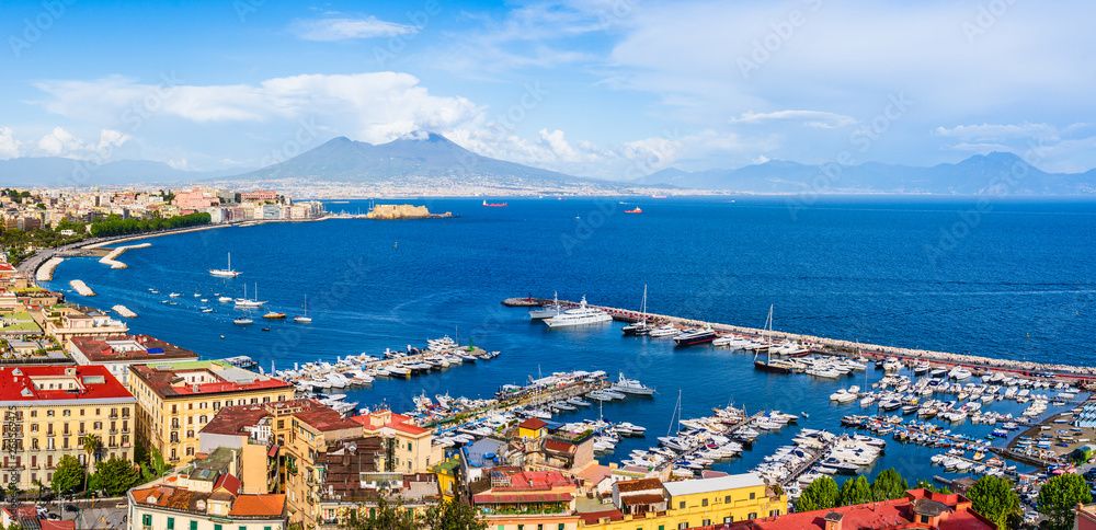 Naples city and port with Mount Vesuvius on the horizon seen from the hills of Posilipo. SSeaside landscape of the city harbor and golf on the Tyrrhenian Sea