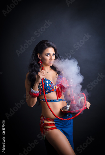Portrait of a beautiful oriental girl in a sexy costume. girl smokes a hookah and exhales smoke