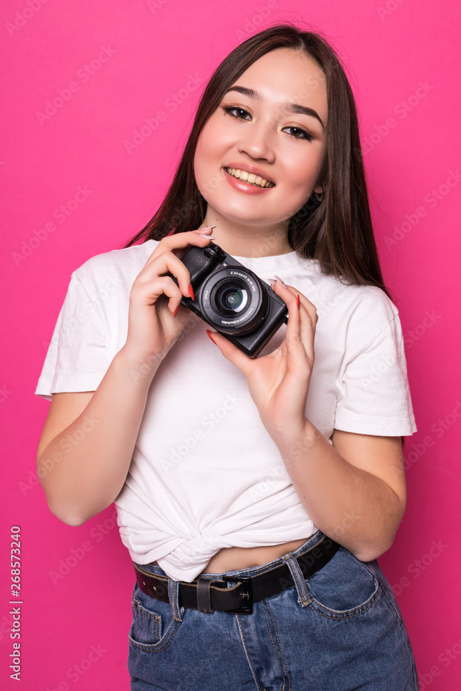 Young pretty asian tourist woman with camera standin isolated on pink background Young pretty asian tourist woman with camera standin isolated on pink background