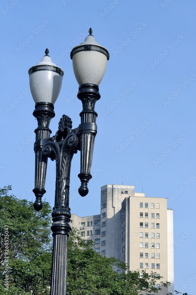 Ancient lamppost in highlighted under sky and buildings