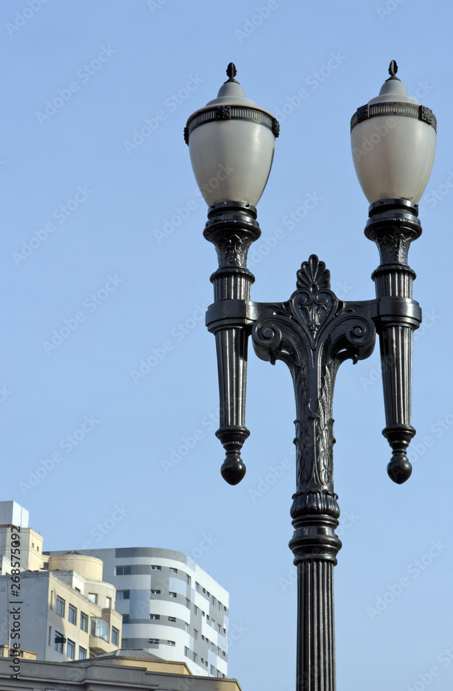 Ancient lamppost in highlighted under sky and buildings