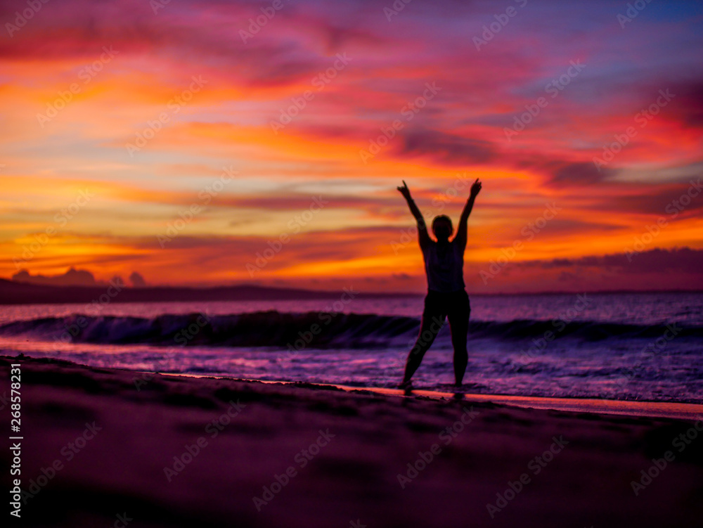 Fototapeta premium Silhouette of a woman on the beach at sunset