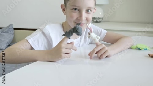 A caucasian boy playing finger puppets, toys, dolls - figures of animals, heroes of the puppet theatre put on fingers of human hand photo