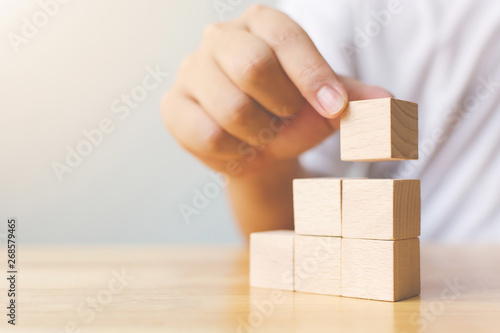 Hand arranging wood block stacking as step stair on top. Business concept for growth success process