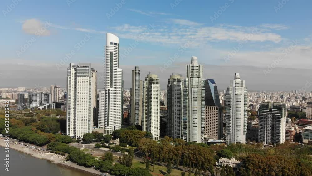 Aerial view of the skyscrapers in Puerto Madero, Buenos Aires with the city skyline as background on a clear day. Drone flying foreward and approaching the skyscrapers. Aerial view of the skyscrapers in Puerto Madero, Buenos Aires with the city skyline as background on a clear day. Drone flying foreward and approaching the skyscrapers.