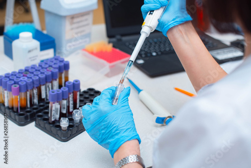 Blood test in the laboratory. Laboratory assistant working with the dispenser. Vacuum tubes with blood