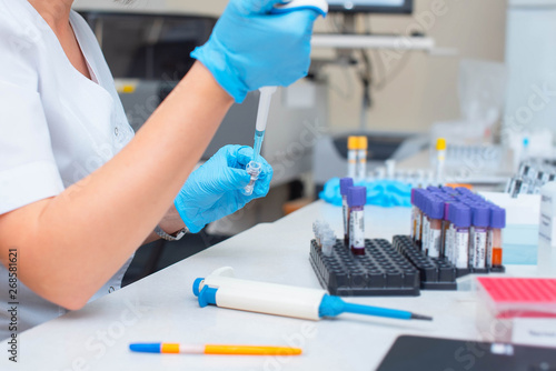 Blood test in the laboratory. Laboratory assistant working with the dispenser. Vacuum tubes with blood