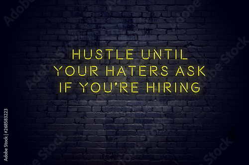 Neon sign with positive wise motivational quote against brick wall 