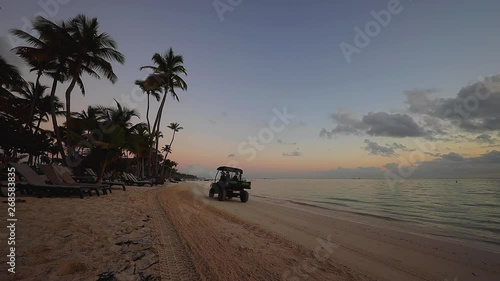 Sunrise over tropical island beach in Punta Cana, Dominican Republic. Tractor cleaning the seand photo