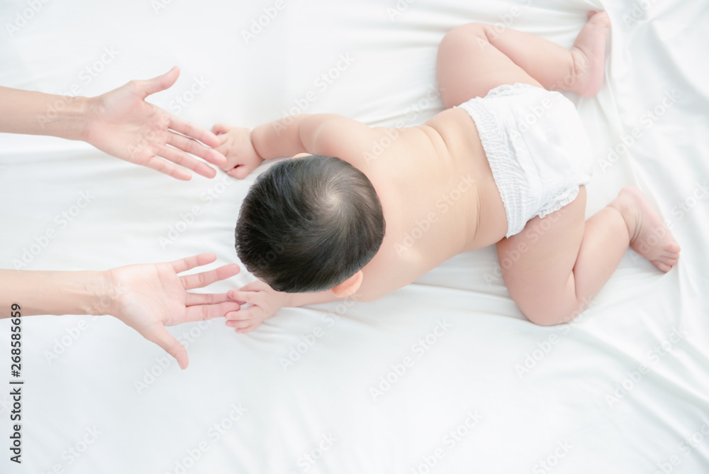 Asian smiling baby boy play and crawling to his mother in living room, Mother extend hand to coming together help baby feel confident. Baby skills develop concept.