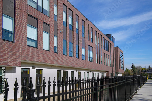 Modern brick school building surrounded by black metal fence