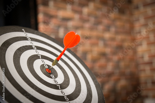 Red dart arrow hitting in the target center of dartboard on bullseye with sun light vintage style, Target marketing and business success concept - Image.
