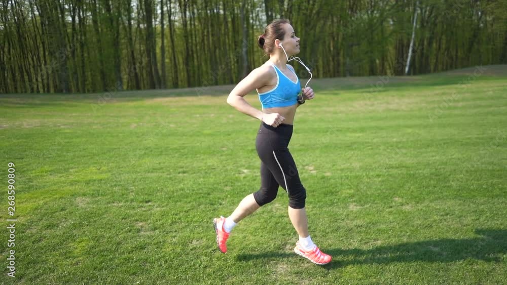 Slow motion. Fitness woman runner run on green field.Steady shot Slow motion. Fitness woman runner run on green field.Steady shot