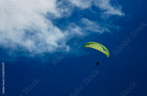 Two paraglider tandem fly against the blue sky,tandem paragliding guided by a pilot