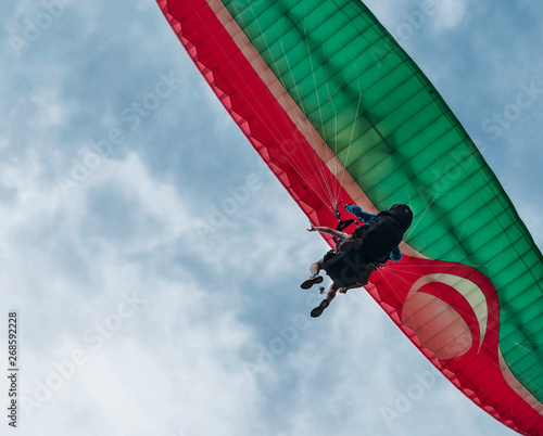 Two paraglider tandem fly against the blue sky,tandem paragliding guided by a pilot