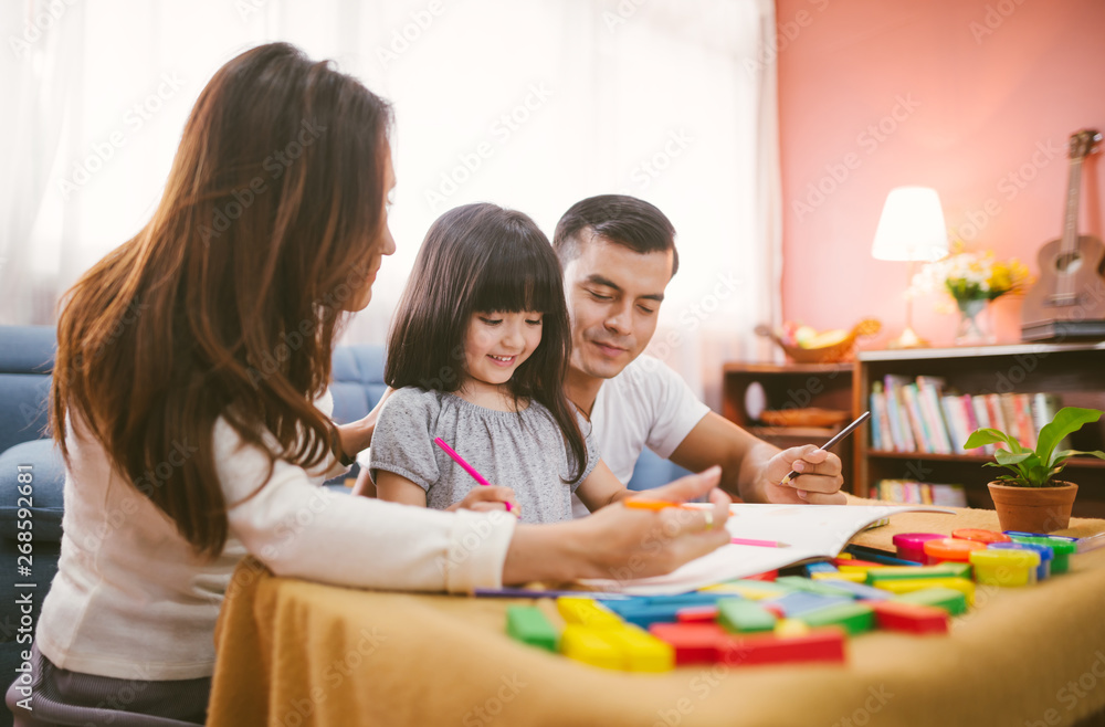 Portrait of happy family daughter girl is learning drawing book together with parent Portrait of happy family daughter girl is learning drawing book together with parent